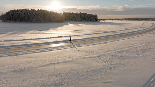 Winter walk in Luleå: Person and dog enjoying a scenic sunset over a frozen river