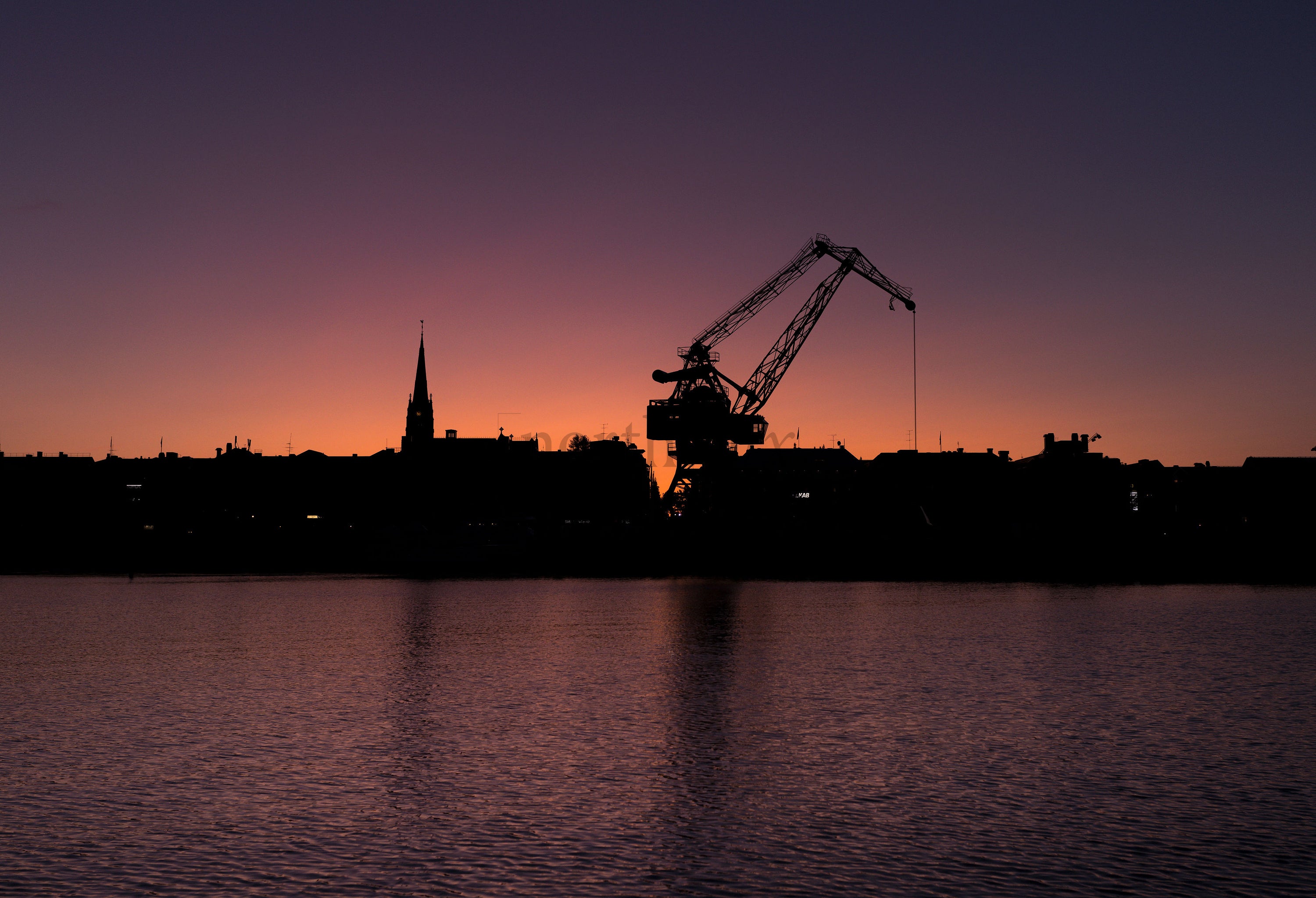 Harbor crane silhouette at sunset over water