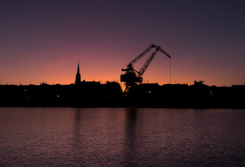 Harbor crane silhouette at sunset over water