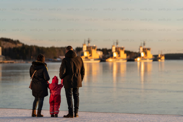 Family on frozen waterfront at sunset