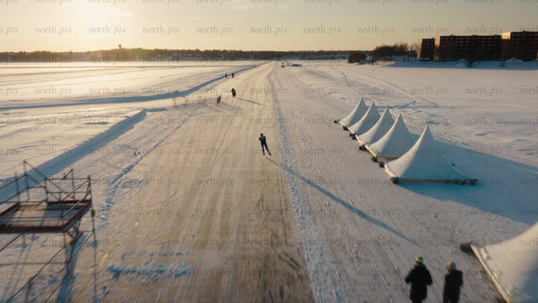 Man speed skating on frozen lake, Luleå - winter sunset aerial drone footage