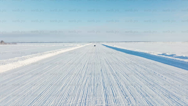 Tesla/car driving on snowy ice road in Luleå - winter drone shot