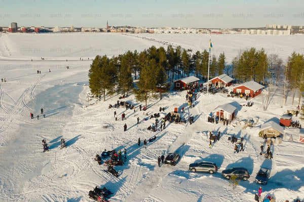 Winter scene at Luleå city center: Snowy park, cabins, and families