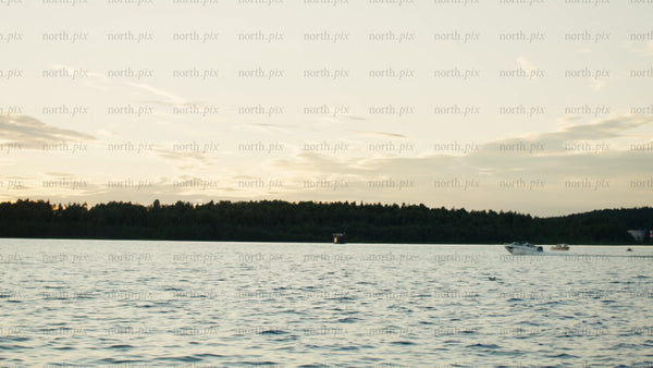 Sunset over the Luleå river: Motorboats sailing on a summer evening