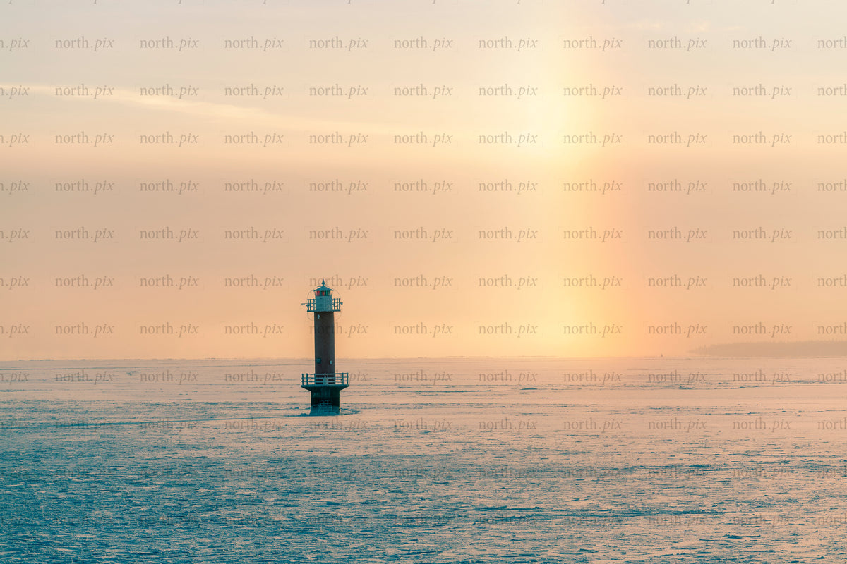 Lighthouse on frozen sea at sunrise