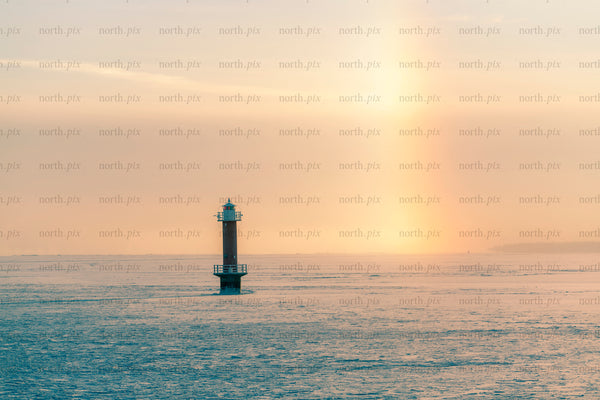 Lighthouse on frozen sea at sunrise