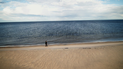 Kvinna som går på sandstrand vid havet på sommaren