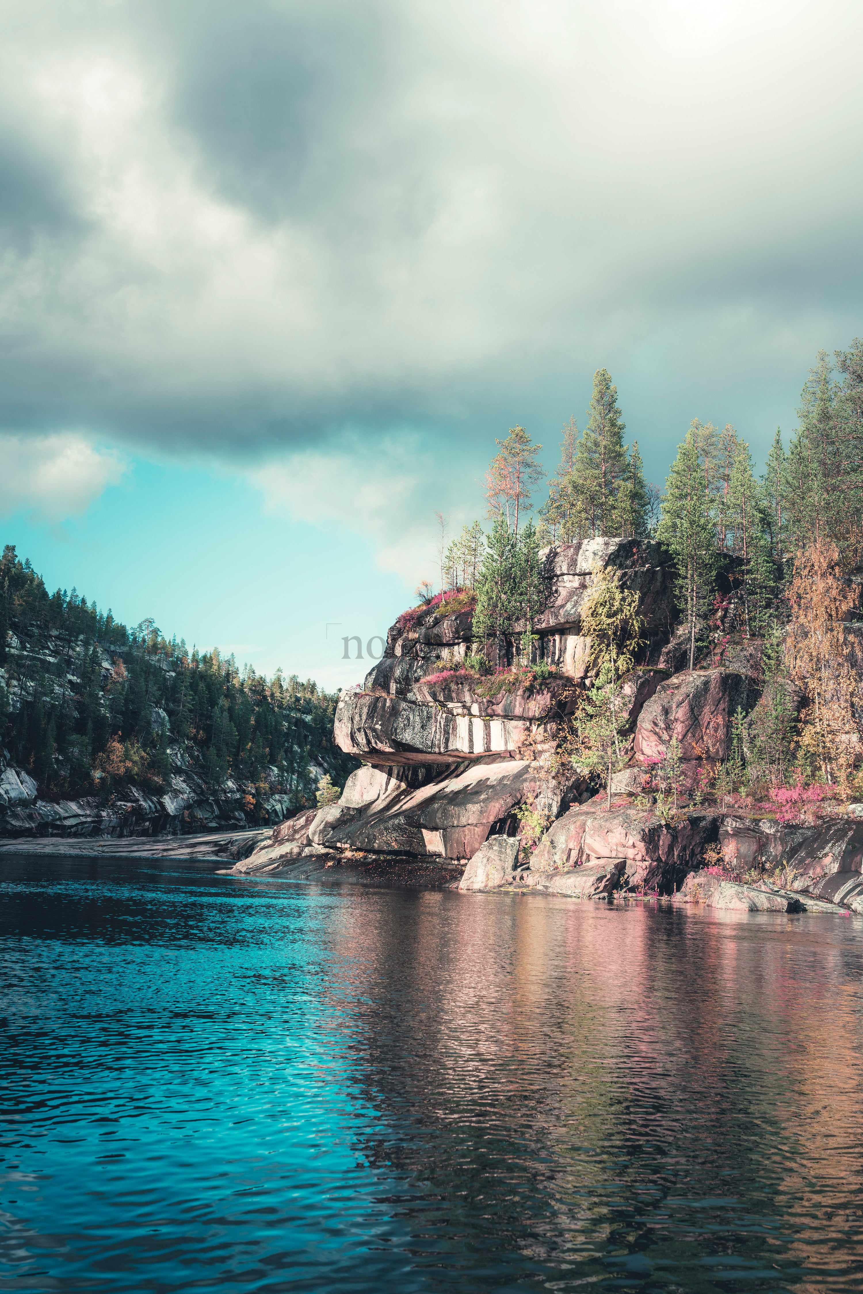 Rocky lakeshore cliff with trees and reflections