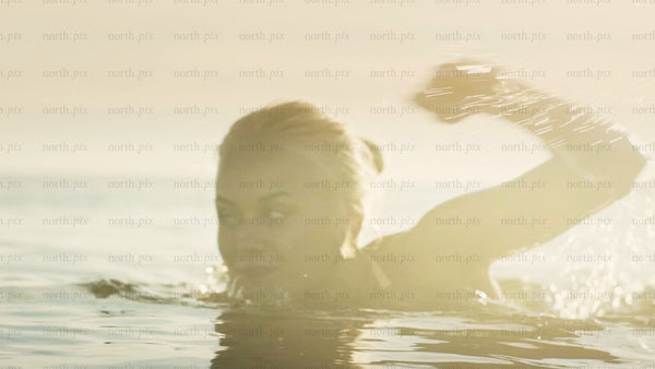 Woman swimming in the Baltic Sea at golden hour in Luleå