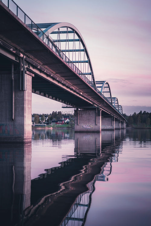 Arch bridge over river at dusk with reflection