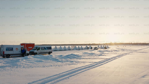 Winter sunset drone shot of snowy Luleå with tents and people on frozen water