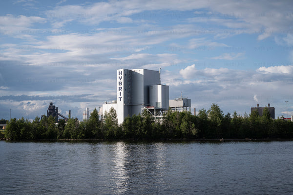 Industrial plant with HYBRIT signage by river in daytime