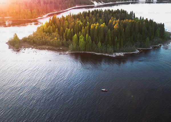 Drone view of lush island with canoe during golden hour evening light