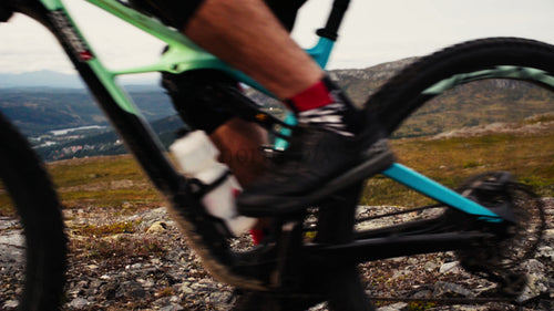 Mountainbiker åker nedförsbacke på stenig stig på sommaren