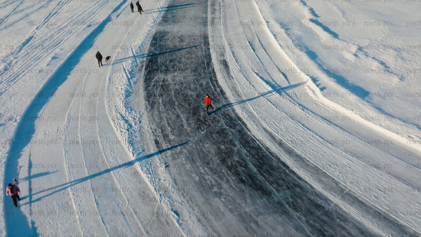 Aerial view of people ice skating and walking on a frozen lake in Luleå