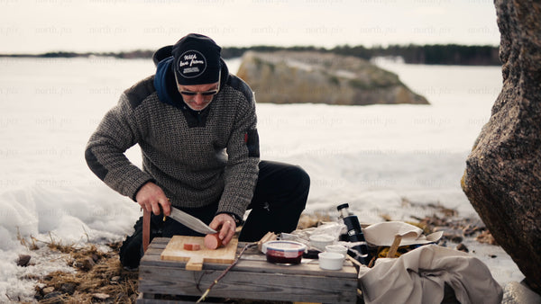Winter picnic in the Luleå archipelago: Man prepares food by a frozen lake