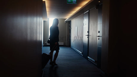 Businesswoman Walking Down Dark Hotel Corridor and Entering Room