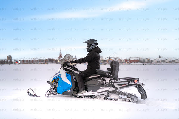 Rider on a snowmobile crossing a frozen lake in winter