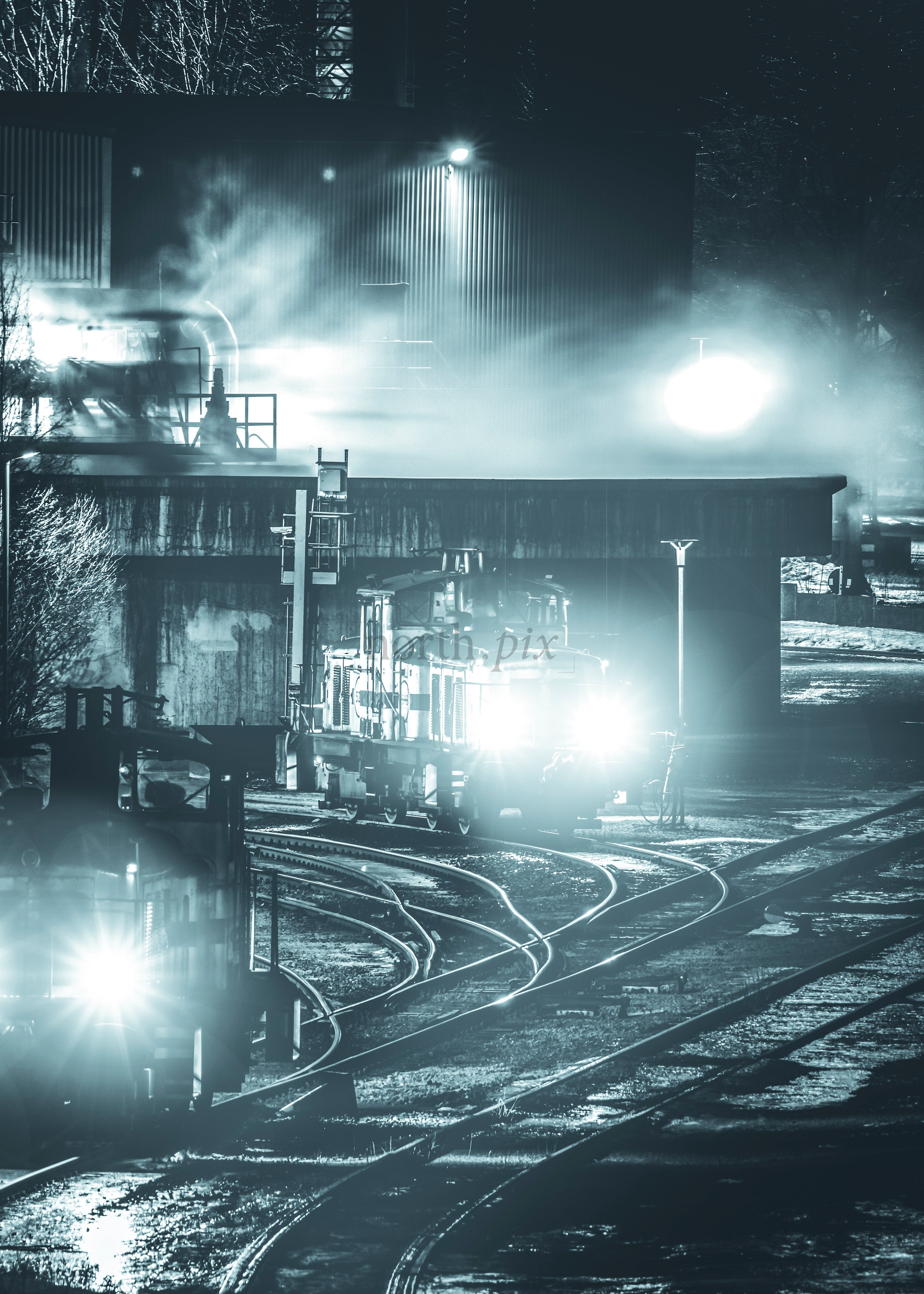 Locomotives in rail yard at night with headlights