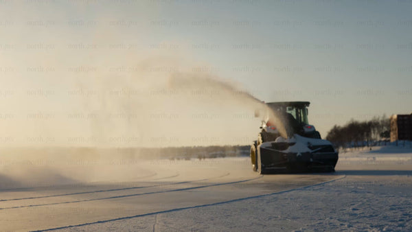 Snow blower tractor clearing frozen lake in Luleå, on a bright winter day