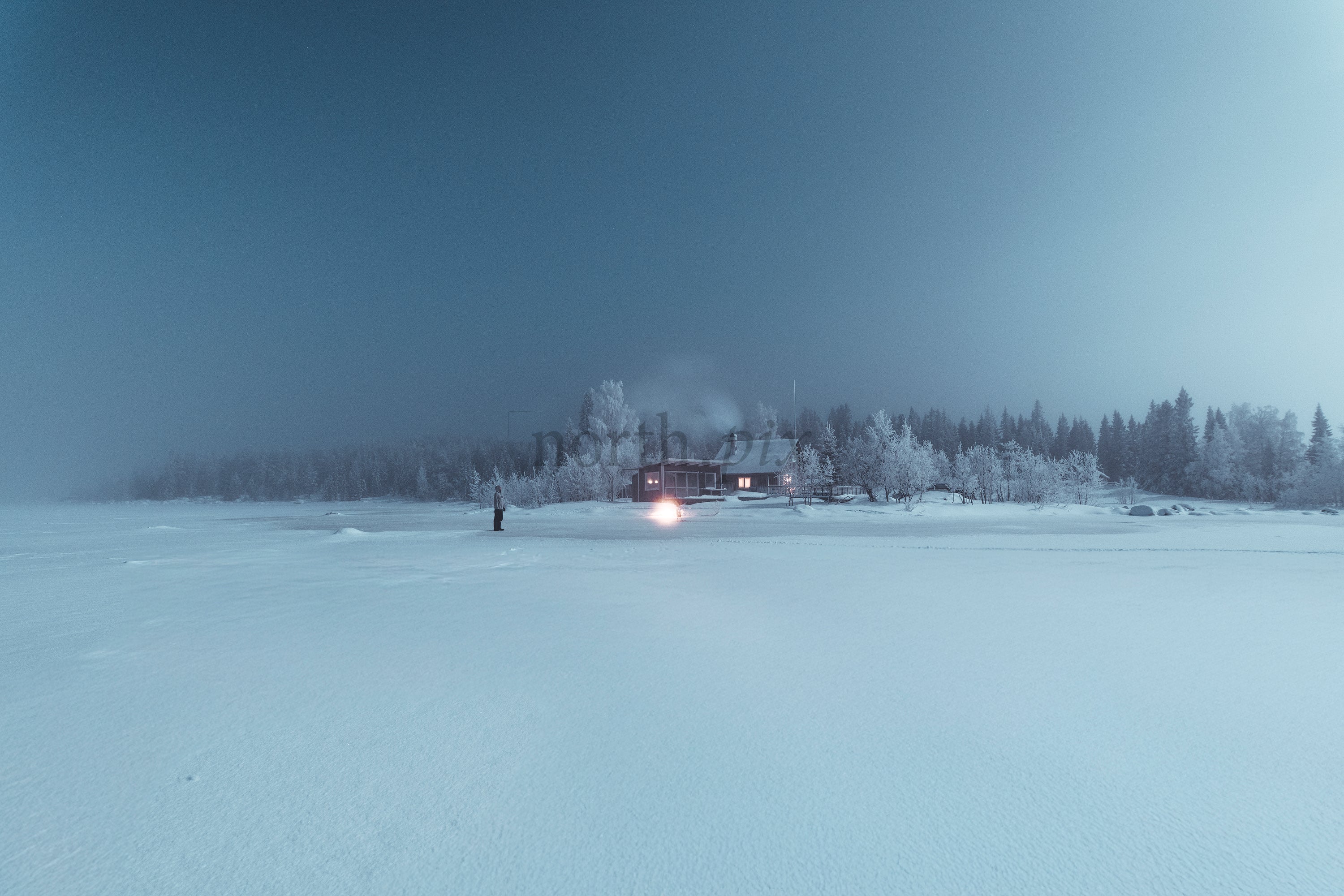 Cabin on a frozen lake at night in winter