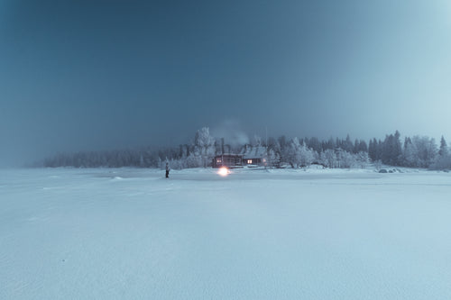 Cabin on a frozen lake at night in winter