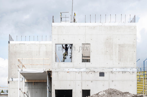 Construction worker in window opening on concrete building, daytime