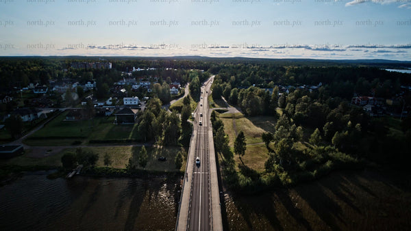 Aerial view of Luleå: Summer evening drive over bridge, lush green landscape