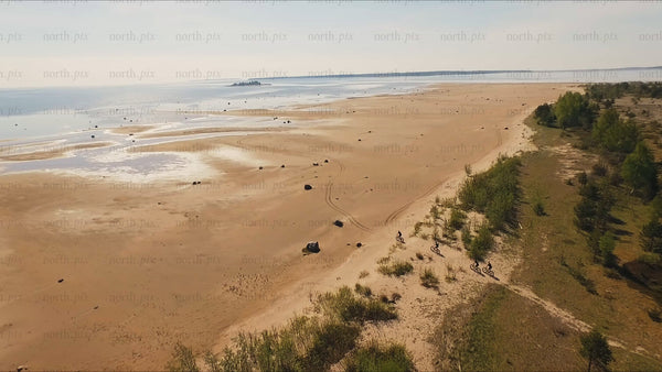 Fat biking on a sandy beach in Luleå, summer day drone shot