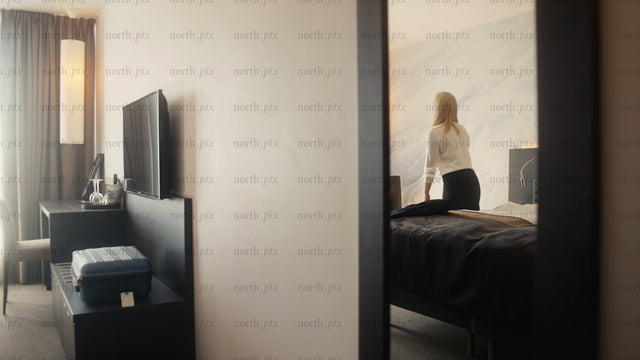 Businesswoman arriving in modern hotel room in Luleå, and relaxing on bed