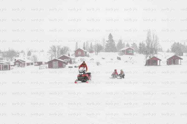 Snowmobile towing sled across frozen lake in winter