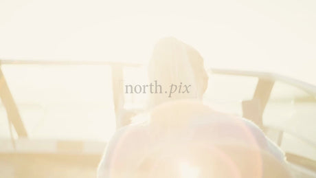Woman Steering Boat in the Luleå Archipelago, Sweden. Summer Sunshine, Lens Flare. Baltic Sea. POV