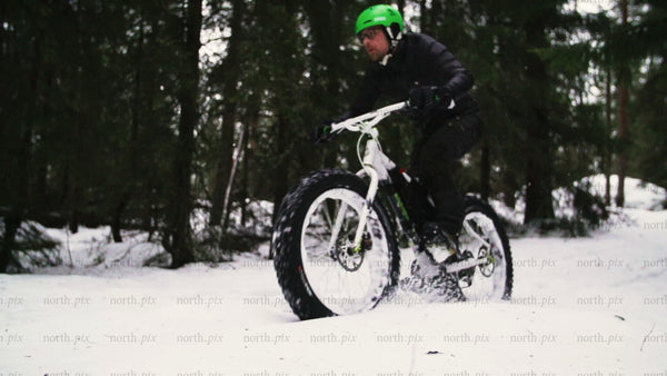 Fatbike riding in snowy forest trail in Luleå, winter day