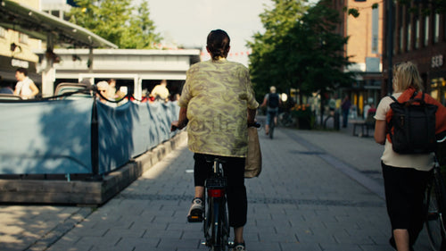 Kvinna på cykel på Luleå stadsgata under solig sommardag