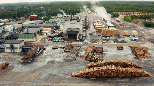 Flygfoto över träbearbetningsfabrik: stockar, virke och industriell verksamhet på sommaren
