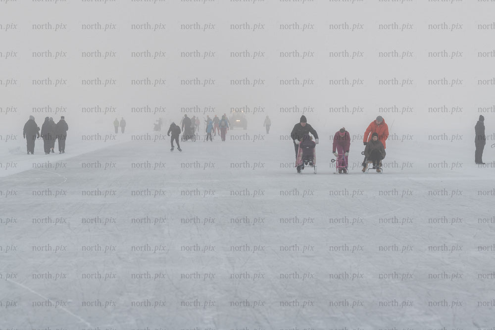 People skating and pushing sleds on frozen lake, winter