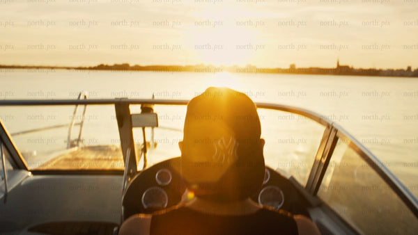 Man driving motorboat in Luleå archipelago at sunset during golden hour
