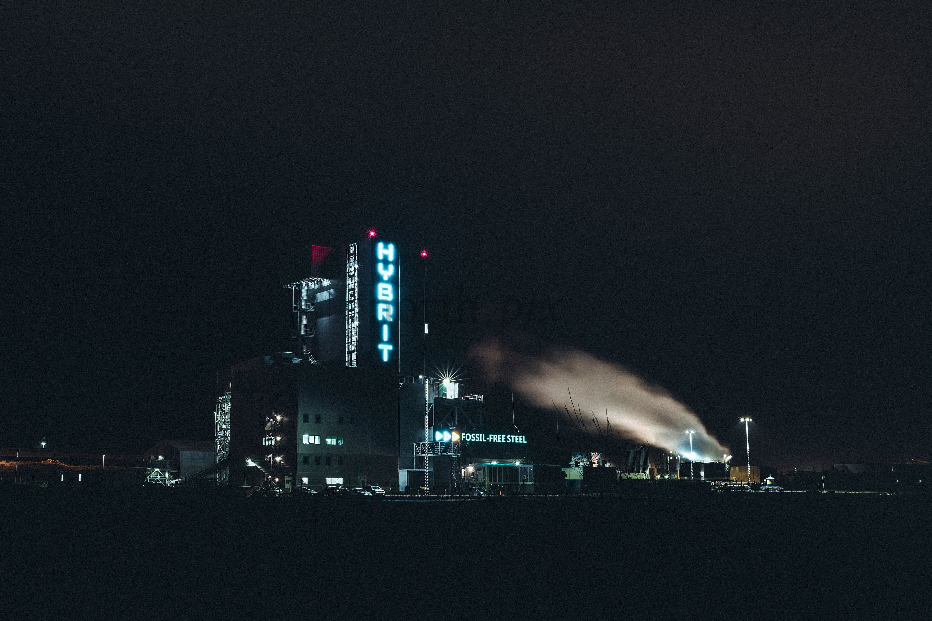 Industrial steel plant at night with illuminated tower