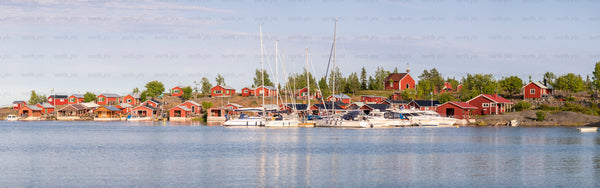 Red boathouses and yachts on archipelago coast, summer morning