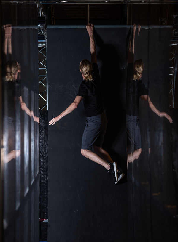 Person hanging from indoor wall with mirrored panels