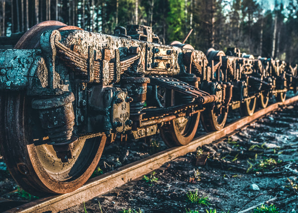 Close-up of rusty train bogie wheels on rails at sunrise