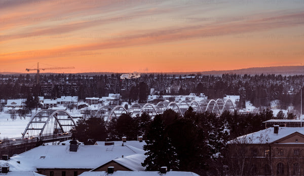 Arched bridge over snowy town at sunset