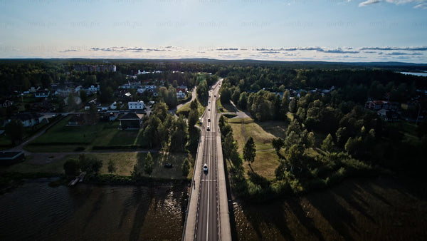 Aerial view of Luleå: Summer evening drive over bridge, lush green landscape