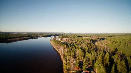 Breathtaking Aerial View of Piteå's Serene River and Lush Forest Landscape Under a Clear Blue Sky