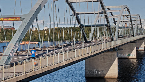 Runner crossing bridge in Luleå on a sunny summer day