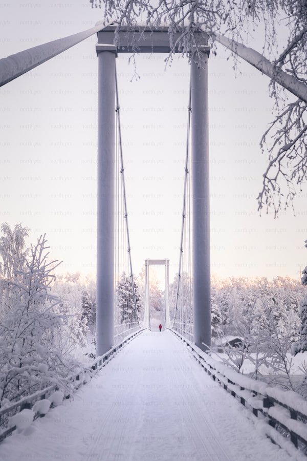Pedestrian suspension bridge covered in snow at dawn