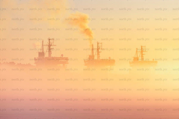 Three icebreakers in fog at sunrise