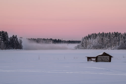 Boathouse on a frozen lake at sunrise