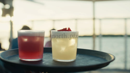 Servitör bär cocktails på en bricka på en urban takfest under en sommarkväll