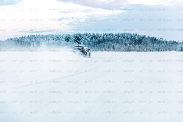Car driving on snowy field near forest, winter